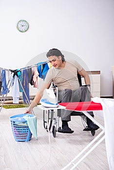 Young man in wheel-chair doing ironing at home