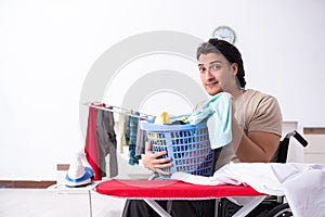 Young man in wheel-chair doing ironing at home