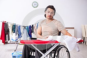 Young man in wheel-chair doing ironing at home