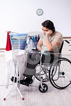 Young man in wheel-chair doing ironing at home