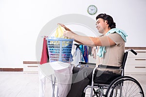 Young man in wheel-chair doing ironing at home