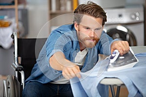 young man in wheel-chair doing ironing at home