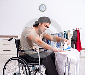 Young man in wheel-chair doing ironing at home