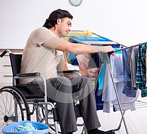 Young man in wheel-chair doing ironing at home