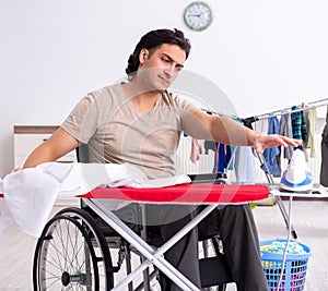 Young man in wheel-chair doing ironing at home