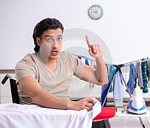 Young man in wheel-chair doing ironing at home