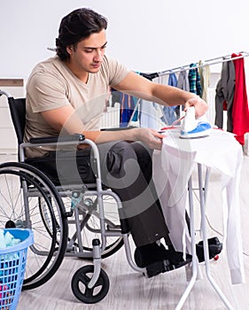Young man in wheel-chair doing ironing at home