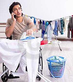 Young man in wheel-chair doing ironing at home