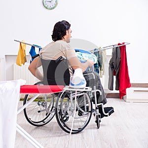 Young man in wheel-chair doing ironing at home