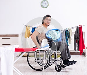 Young man in wheel-chair doing ironing at home