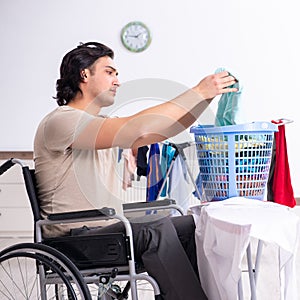 Young man in wheel-chair doing ironing at home