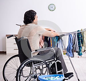 Young man in wheel-chair doing ironing at home