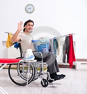 Young man in wheel-chair doing ironing at home