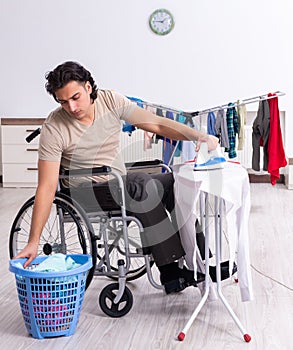 Young man in wheel-chair doing ironing at home