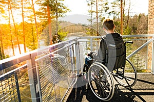 Young man in a wheelchair on a balcony looking at the nature in