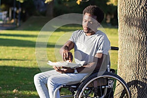 Young man in wheelchair enjoying his snack in park