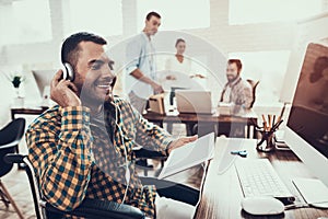 Young Man on Wheelchair with Headphones in Office.