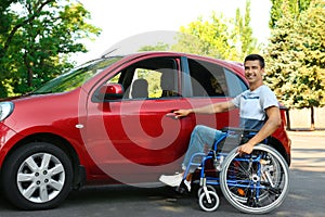 Young man in wheelchair opening door of car