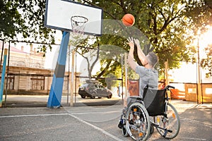 Young man in wheelchair playing basketball outdoors