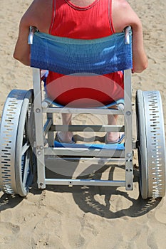 Young man on the wheelchair in the sandy beach in summer