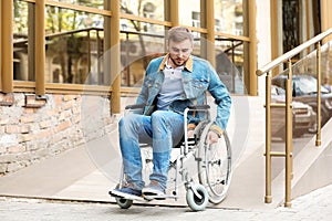 Young man in wheelchair using ramp at building