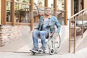 Young man in wheelchair using ramp at building