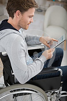 young man in wheelchair using tablet