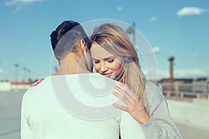 Young man whispering love to blonde woman outdoors