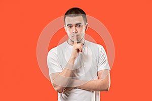 The young man whispering a secret behind her hand over orange background