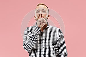 The young man whispering a secret behind her hand over pink background