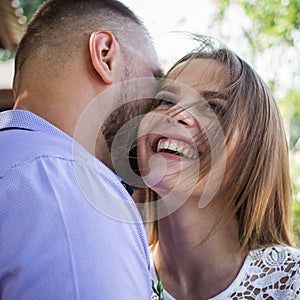 Young man whispering to woman or girlfriend, boyfriend telling surprising secret to his girl, man says nice words to his