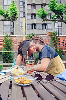 Young man whispering to woman sitting outdoors