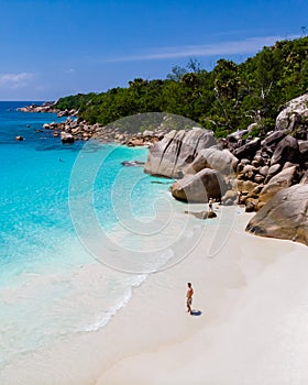 young man on a white beach with turquoise colored ocean, Anse Lazio beach Praslin Island Seychelles