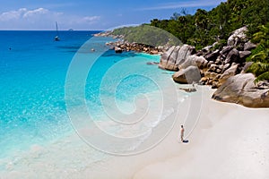 young man on a white beach with turquoise colored ocean, Anse Lazio beach Praslin Island Seychelles