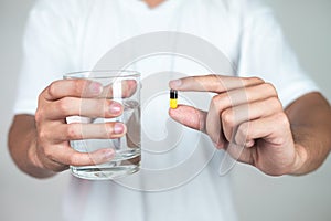 A young man in a white dress is about to eat a pill