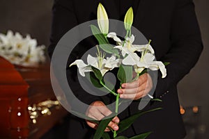 Young man with white lilies in funeral home