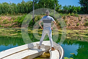 Young man in white pants and modern styling posing in the freshwater pond of Clot De La Mare De Deu in Burriana