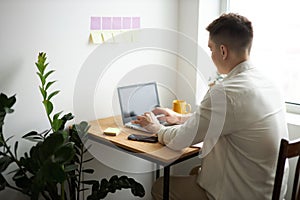 Young man in white shirt using laptop at home
