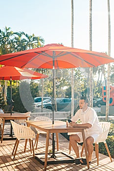 Young man in white shirt working on laptop in outdoor cafe