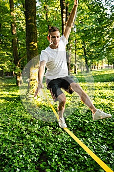 Young man in white tshirt and shorts on the rope keeping balance