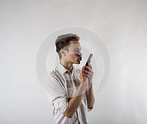Young man in white using smartphone. Man taking selfie over bright background
