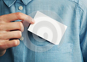 Young man who takes out blank business card from the pocket of his shirt