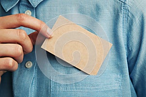 Young man who takes out craft blank business card from the pocket of his shirt