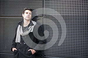 Young Man in a Winter Outfit Leaning on Metal Wall
