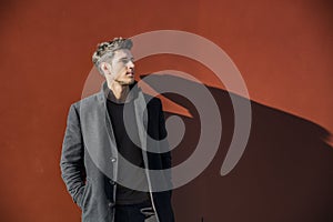 Young Man in a Winter Outfit Leaning on Red Wall