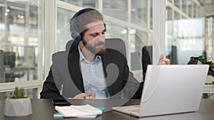 Young man with wireless headset playing on virtual guitar during break in office