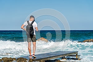 Young man on wod pier at wavy crystal sea