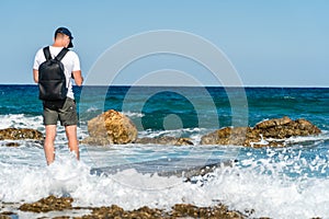 Young man on wod pier at wavy crystal sea