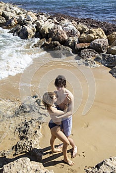 young man and woman about 20 years old, a couple in love, in full growth gently hugging on the beach