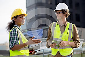 Young man and woman is architect planning and inspector project and looking digital tablet at construction site.